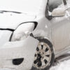 Crashed small car in winter with damaged front quarter panel and wheel
