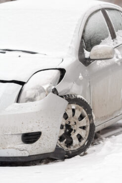 Crashed small car in winter with damaged front quarter panel and wheel