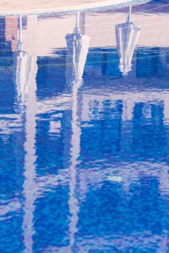 Pool in tourist resort with reflection of umbrellas on water surface